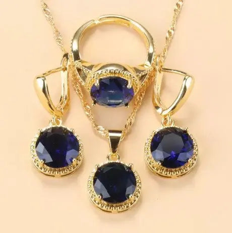 Ensemble de bijoux Ramiart doré avec pierres bleu foncé sur collier, bague et boucles d’oreilles. Idéal pour soirées et événements chics.
