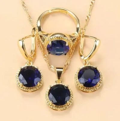 Ensemble de bijoux Ramiart doré avec pierres bleu foncé sur collier, bague et boucles d’oreilles. Idéal pour soirées et événements chics.