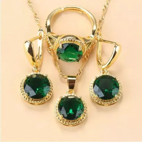 Parure Ramiart dorée avec pierres vert émeraude sur collier, bague et boucles d’oreilles. Bijoux luxueux pour femmes élégantes.