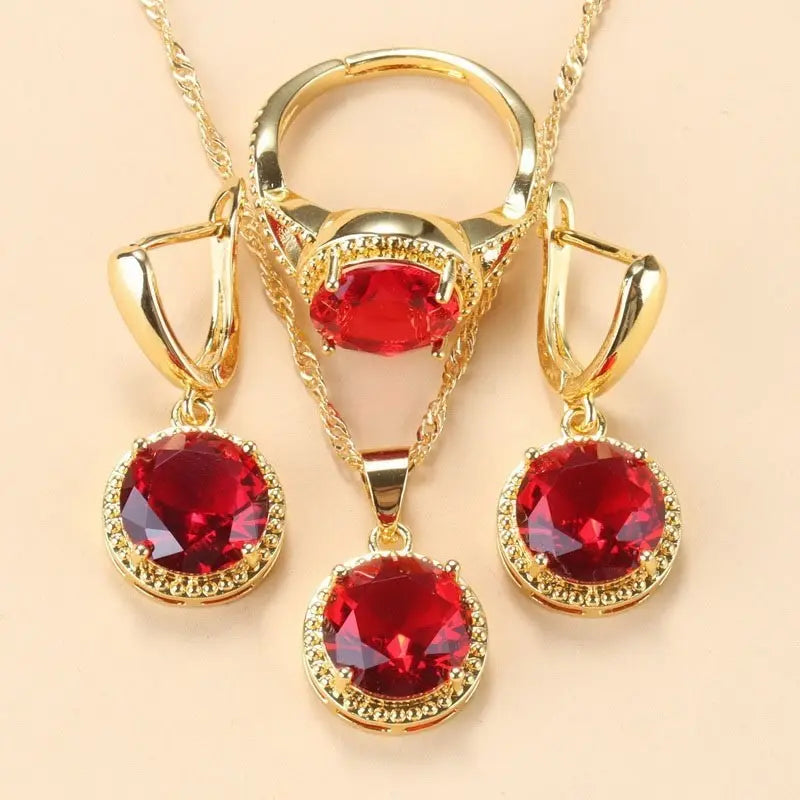 Parure Ramiart trois pièces dorée avec pierres rouges éclatantes. Collier, bague et boucles d’oreilles pour un look glamour et audacieux.